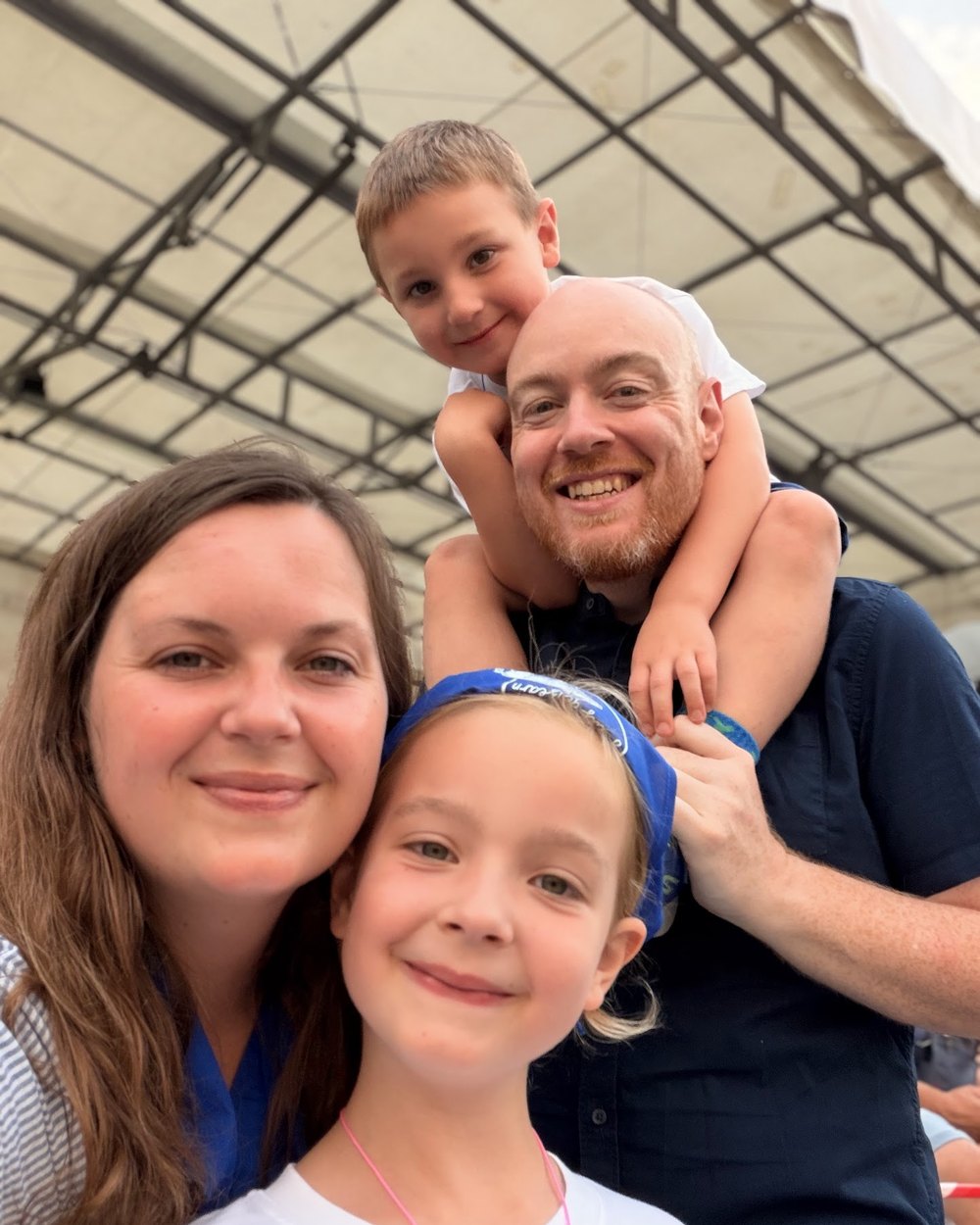 Dan, Julia and their two children, six and seven, smiling together at a summer event.