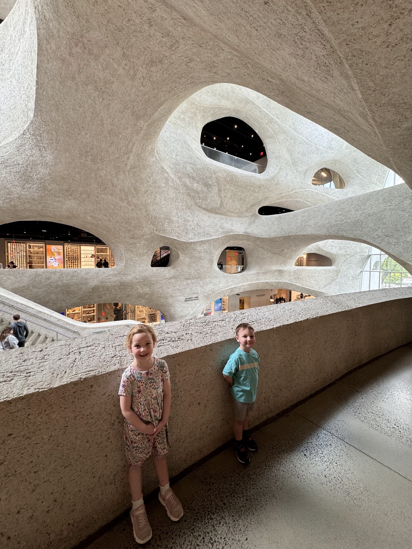 Two children on a walkway inside the white, cave-like atrium of the Gilder Center.