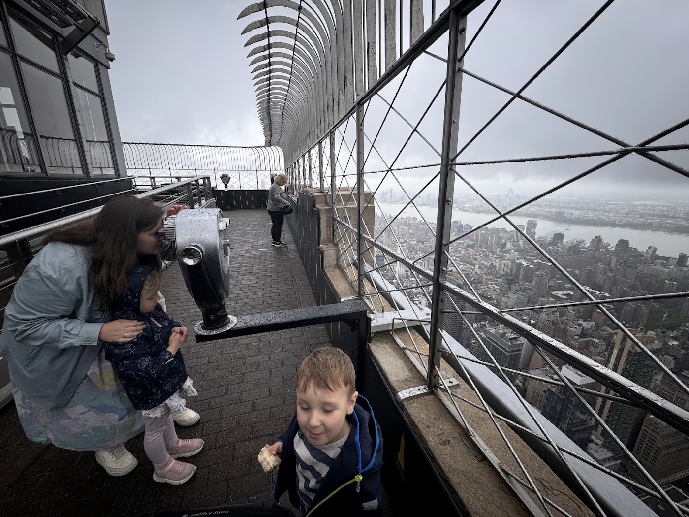 Two children on an observation deck behind curved railings, with cloud where the view should be.