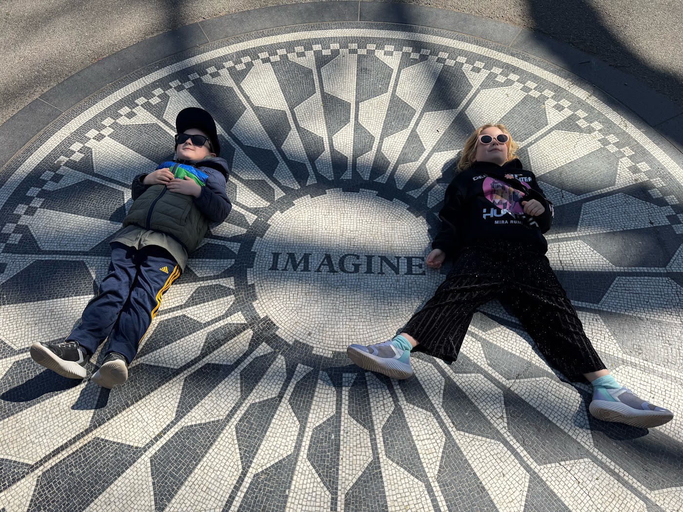 Two children lying on the circular black and white Imagine mosaic.