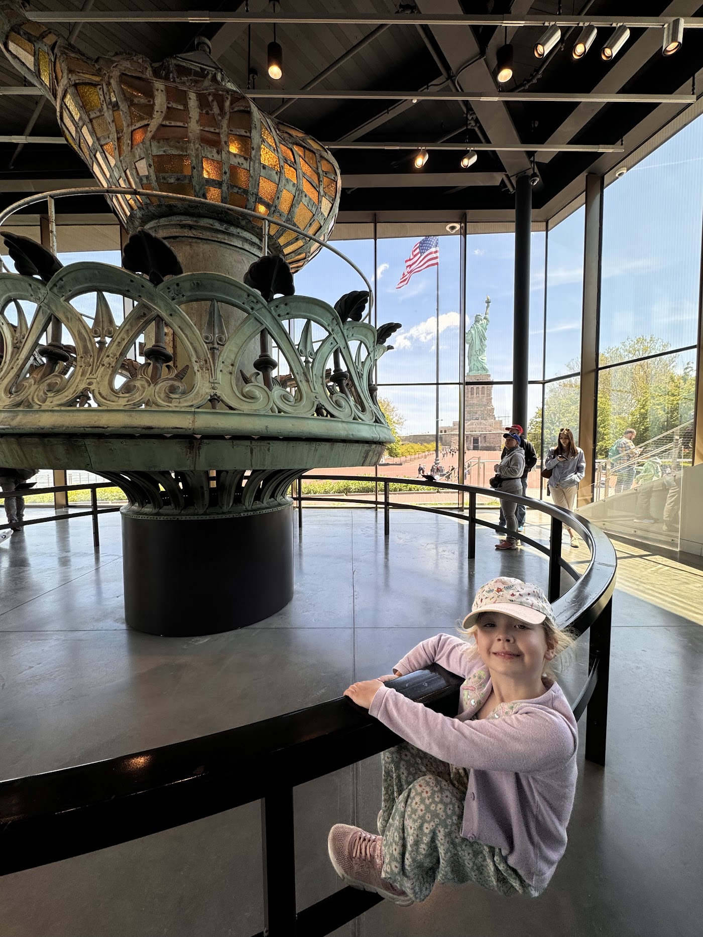 A child next to the glass-paneled original torch of the Statue of Liberty.