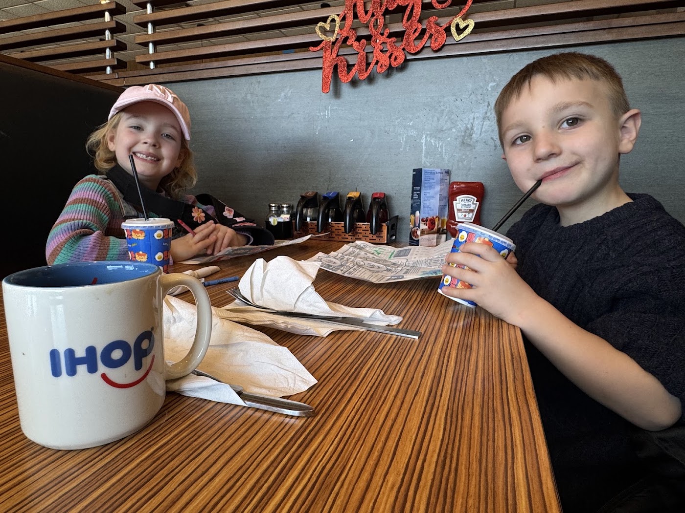 Two children at a table inside Nathan's with drinks and a tray of food.