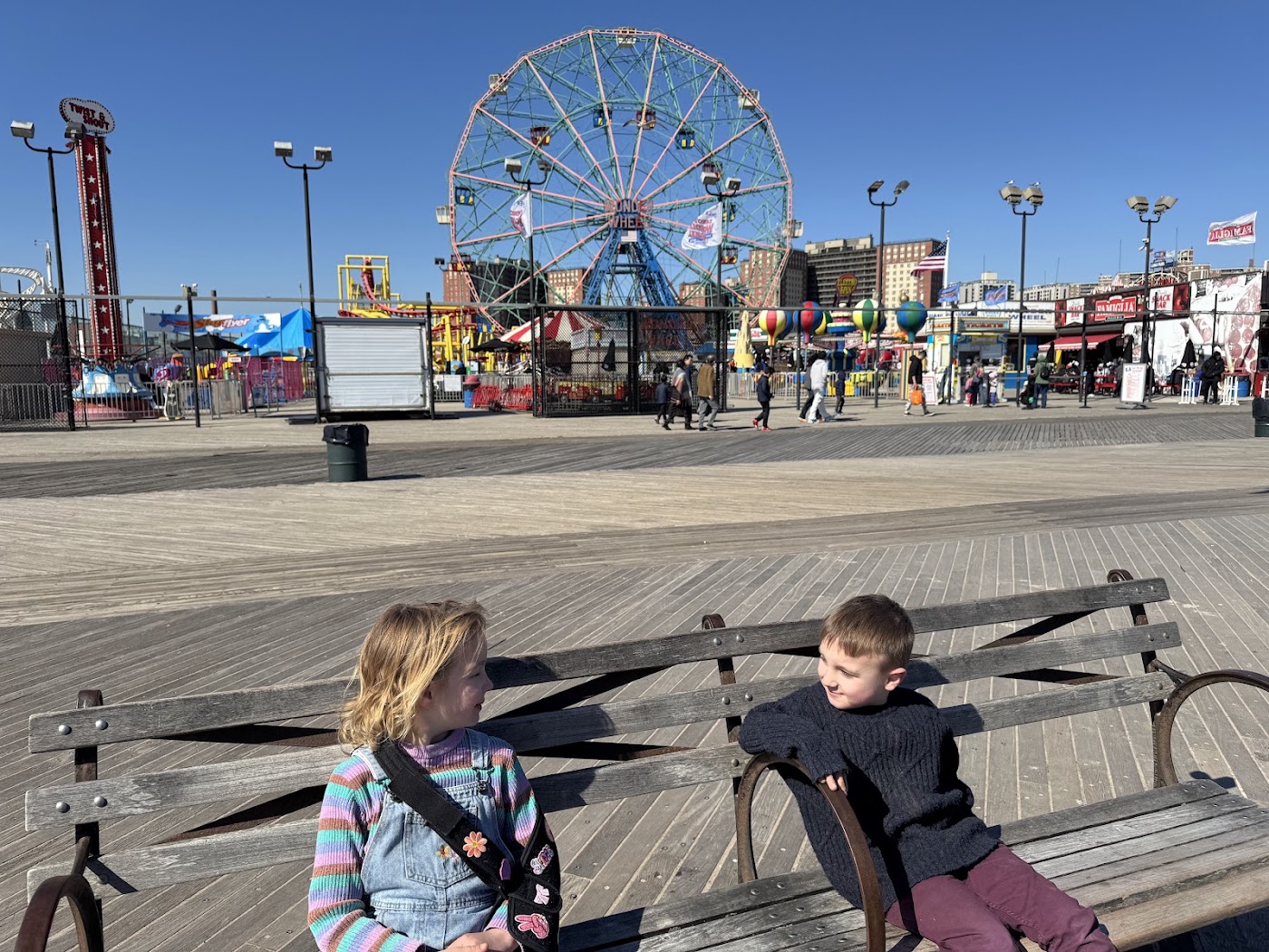 Two children on the boardwalk with the Wonder Wheel and its sign behind them.