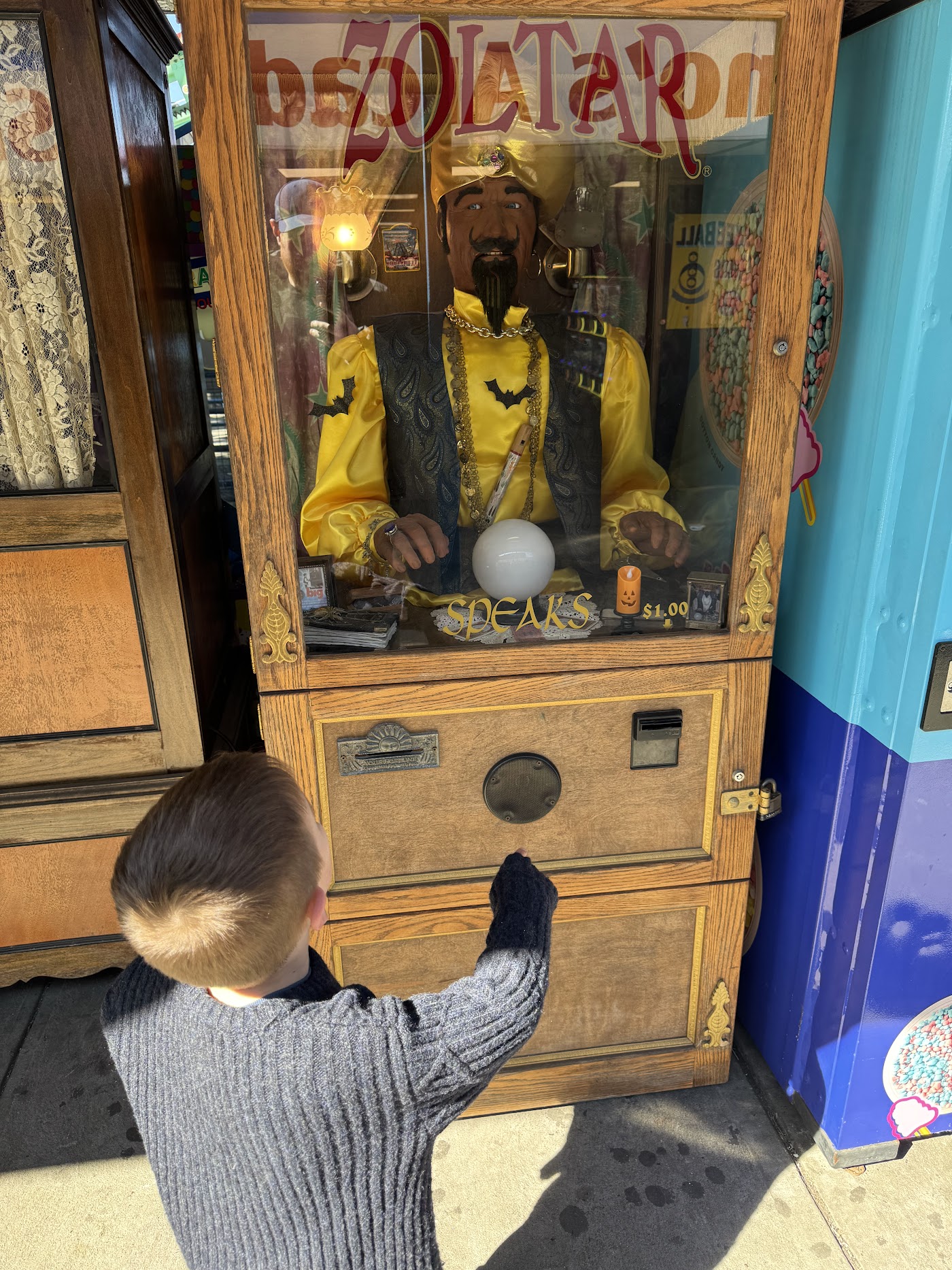 A child looking up at a Zoltar fortune-telling machine in an arcade.